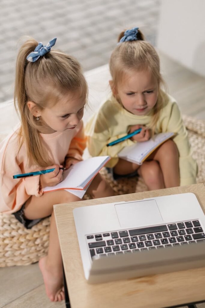 two girls having an online class while writing